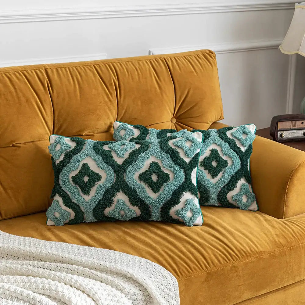 Two teal and white geometric pillow covers on a mustard-yellow velvet sofa featuring decorbites boho tufted design