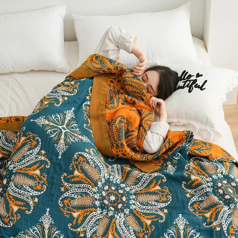 A cozy teal and gold floral decorbites bohemia cotton blanket with paisley pattern draped over a person sleeping