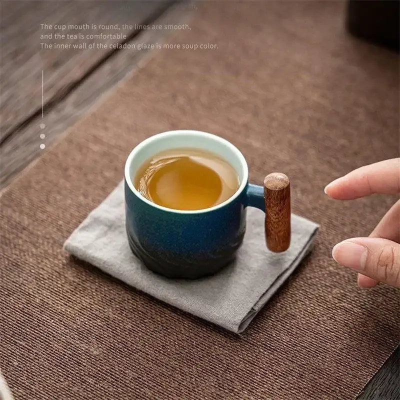 A ceramic coffee cup with teal gradient glaze and wooden handle filled with amber tea for kitchen use