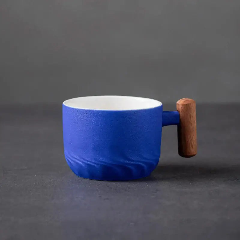 Teal gradient and black ceramic coffee cup with wooden handle and white interior for stylish kitchen use