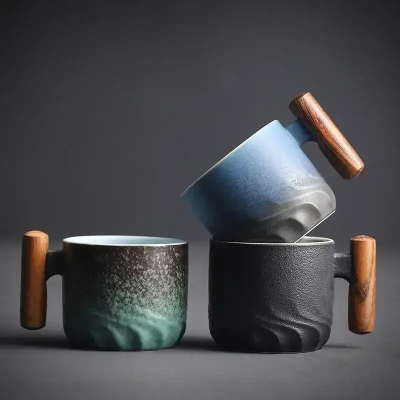 Two ceramic coffee cups with wooden handles featuring a teal gradient glaze and textured black finish for kitchen use