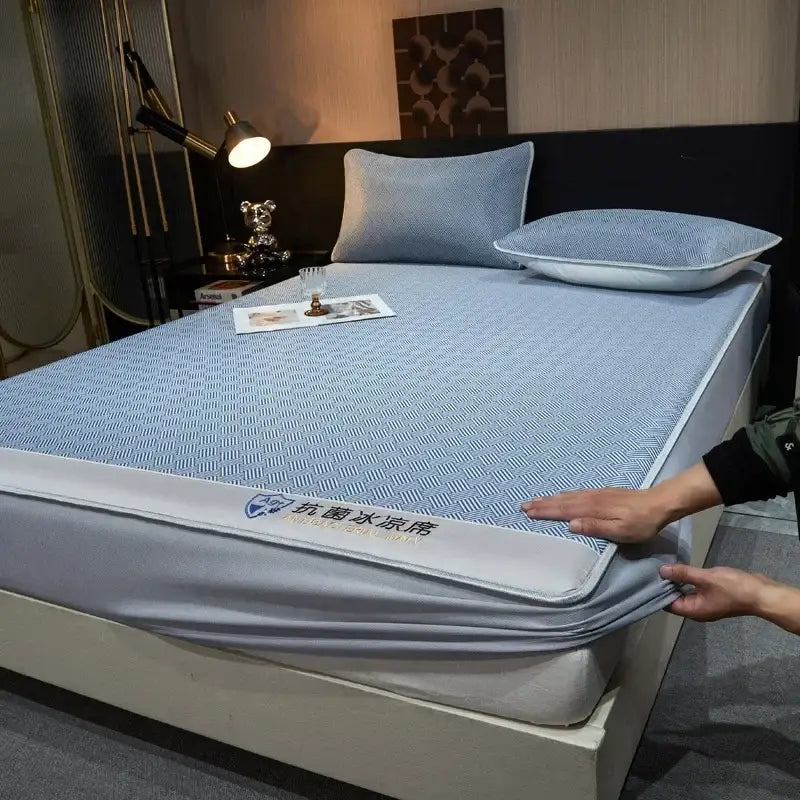 Blue patterned mattress protector with gray trim and branded label paired with teal herringbone silky soft fitted sheet set