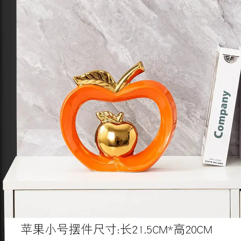 Teal and orange gold plated ceramic apple storage box with an orange apple sculpture and smaller golden apple inside