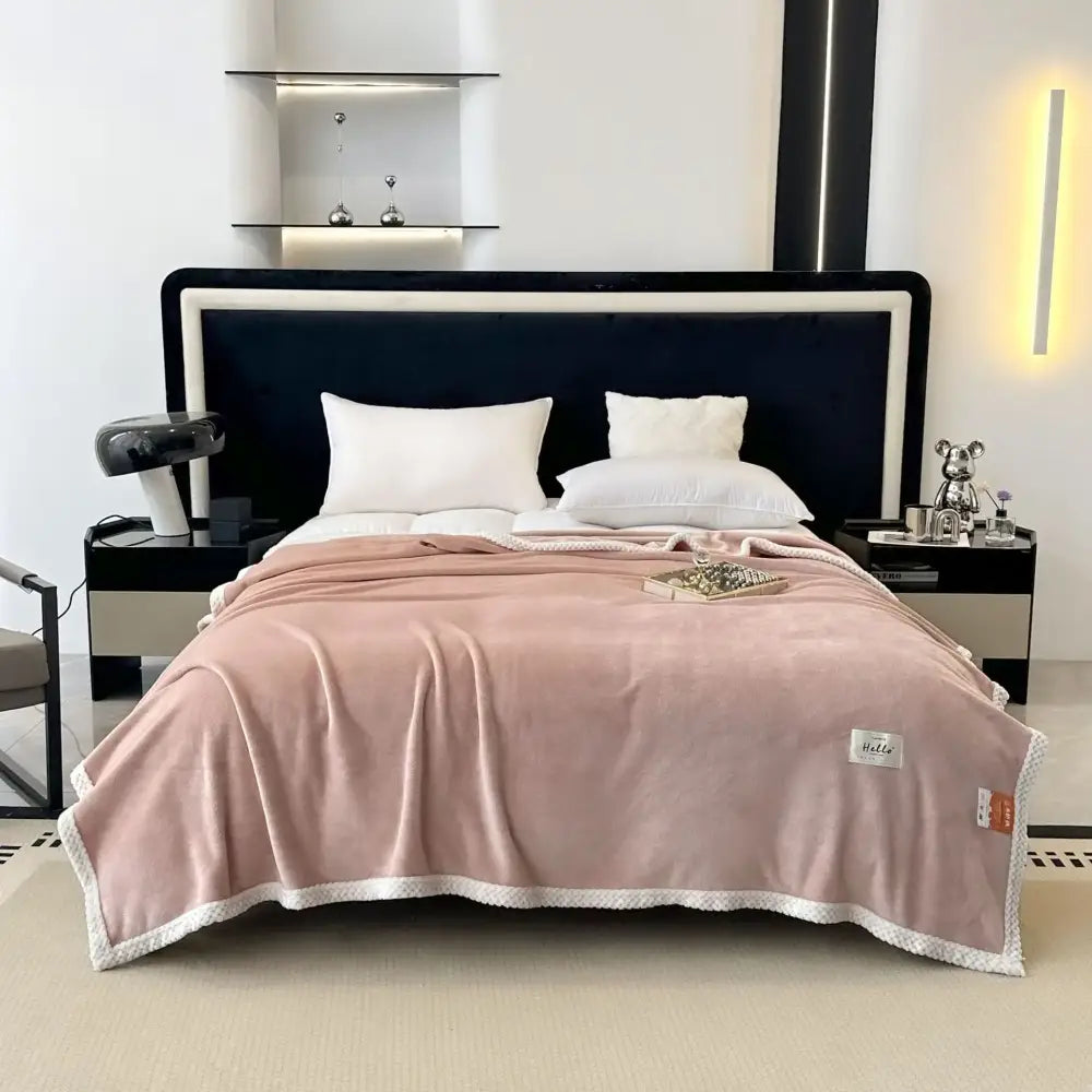 A soft pink plush cozy flannel nap blanket with white textured border and subtle stitching details for bedroom use