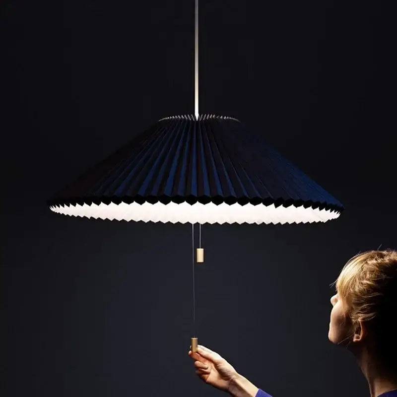 Black pleated paper pendant lamp with white illuminated underside and brass pull chain from decorbites deformed fabric umbrella collection