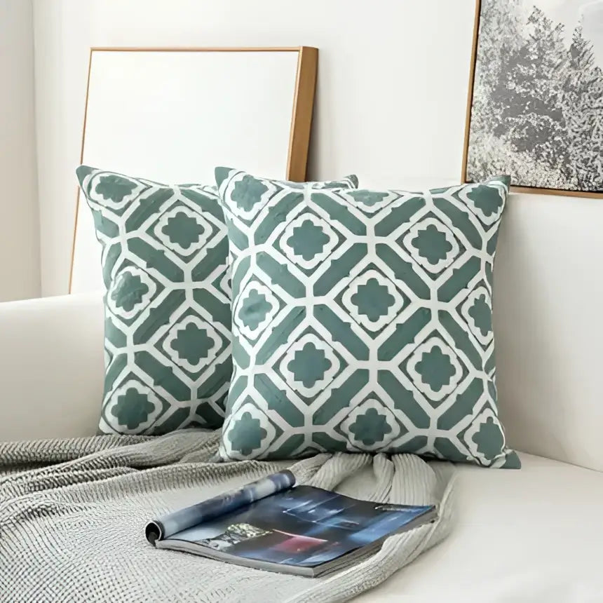Two sage green and white woven throw pillows featuring an embroidered geometric floral cushion cover design