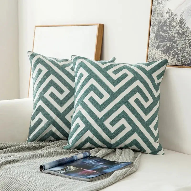 Two square teal and white embroidered geometric floral cushion covers with textured fabric for living room use