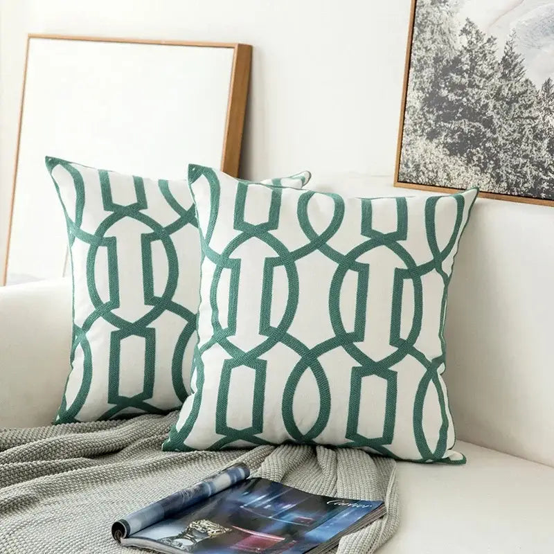 Two square cushion covers in white with teal embroidered geometric floral pattern made of soft fabric for living room