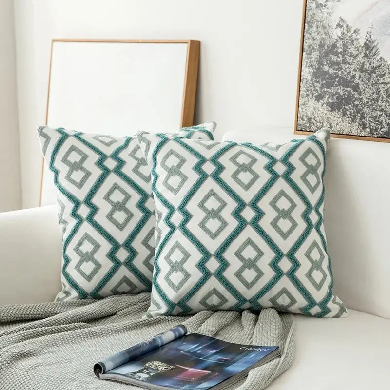 Two square teal and white cushion covers with embroidered geometric floral pattern and textured borders for living room