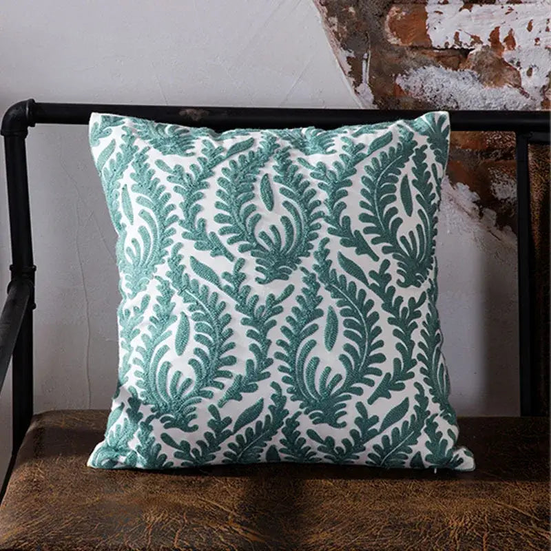 A square cushion cover with a white base and teal embroidered fern patterns perfect for decorbites blue geometric decor