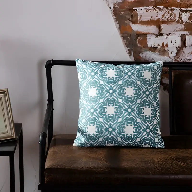 Teal and white blue geometric embroidered cushion cover with intricate design on dark brown leather bench decorbites decor