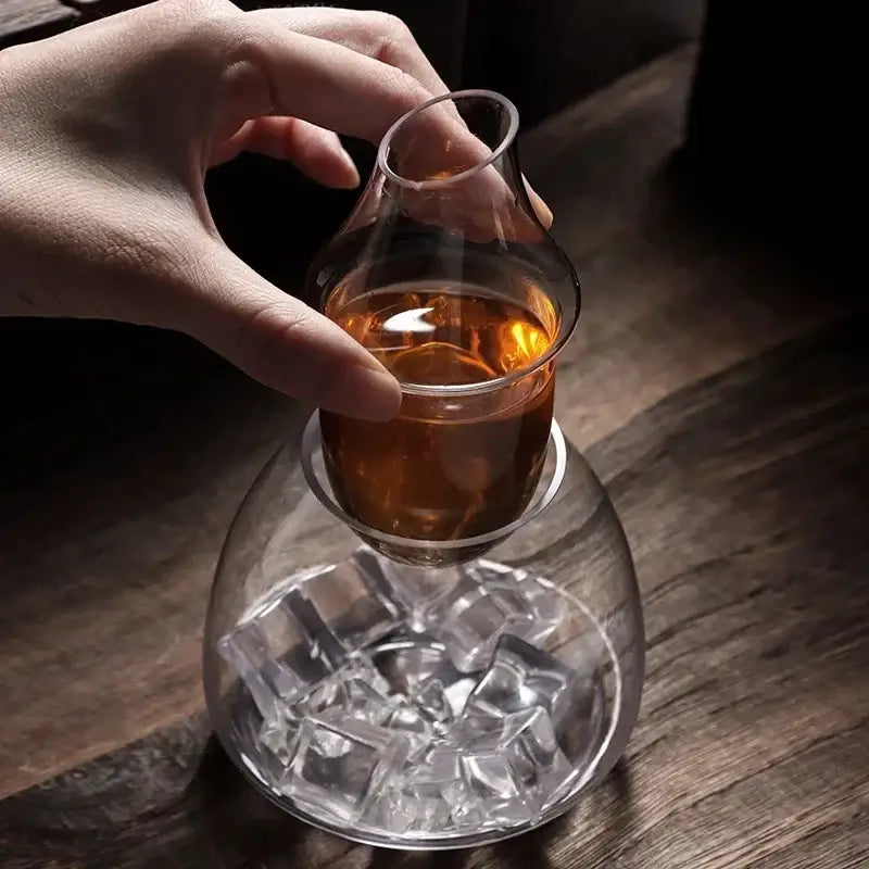 Clear glass wine pot with bulbous base filled with ice cubes and slender glass wine vessel for dining room and bar