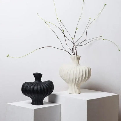 White ceramic fringe heterophore vase with vertical ribbed texture and slender neck holding green branches for decorbites decor