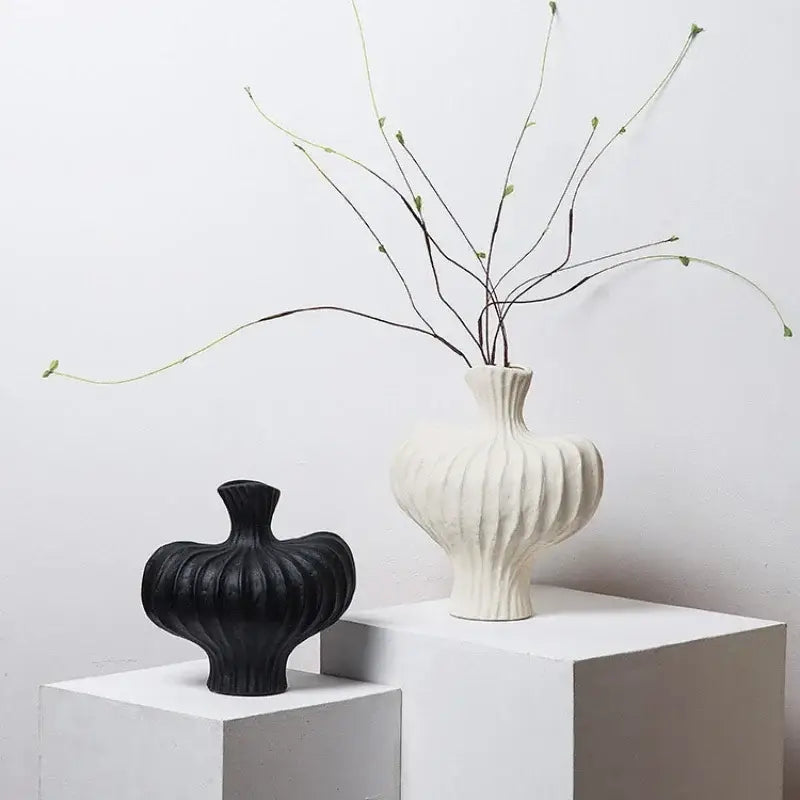 White ceramic fringe heterophore vase with vertical ribbed texture and slender neck holding green branches for decorbites decor