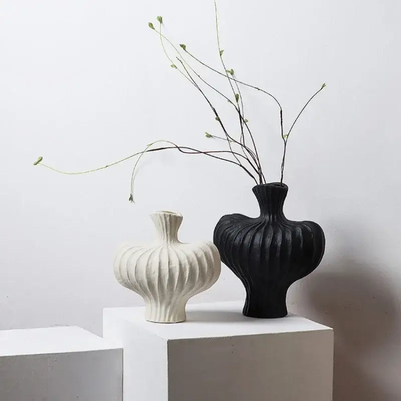 Black ceramic fringe heterophore vase with vertical ridges and flared neck paired with smaller off-white ceramic decorbites vase