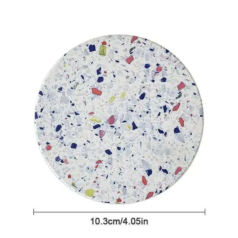 Circular decorbites diatomite coaster with white terrazzo finish featuring red blue green and gray mosaic fragments