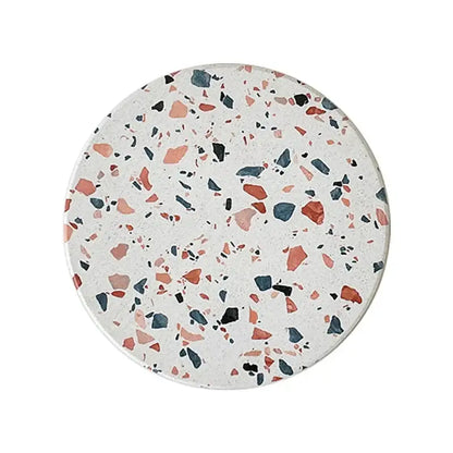 Circular terrazzo decorbites diatomite coaster with white base and pink, orange, blue, and black fragments for dining use