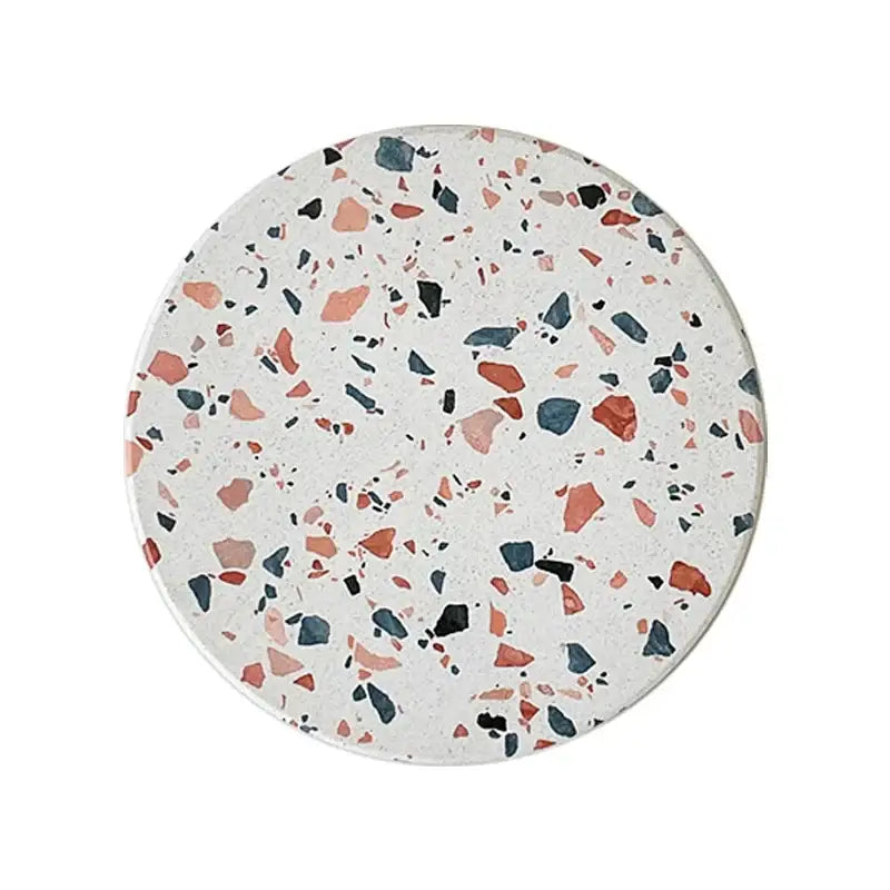 Circular terrazzo decorbites diatomite coaster with white base and pink, orange, blue, and black fragments for dining use