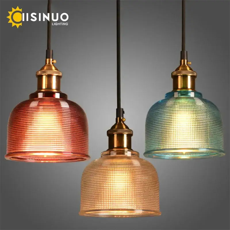 Three glass pendant lights with textured amber gold and teal shades and brass-finished fixtures for dining rooms