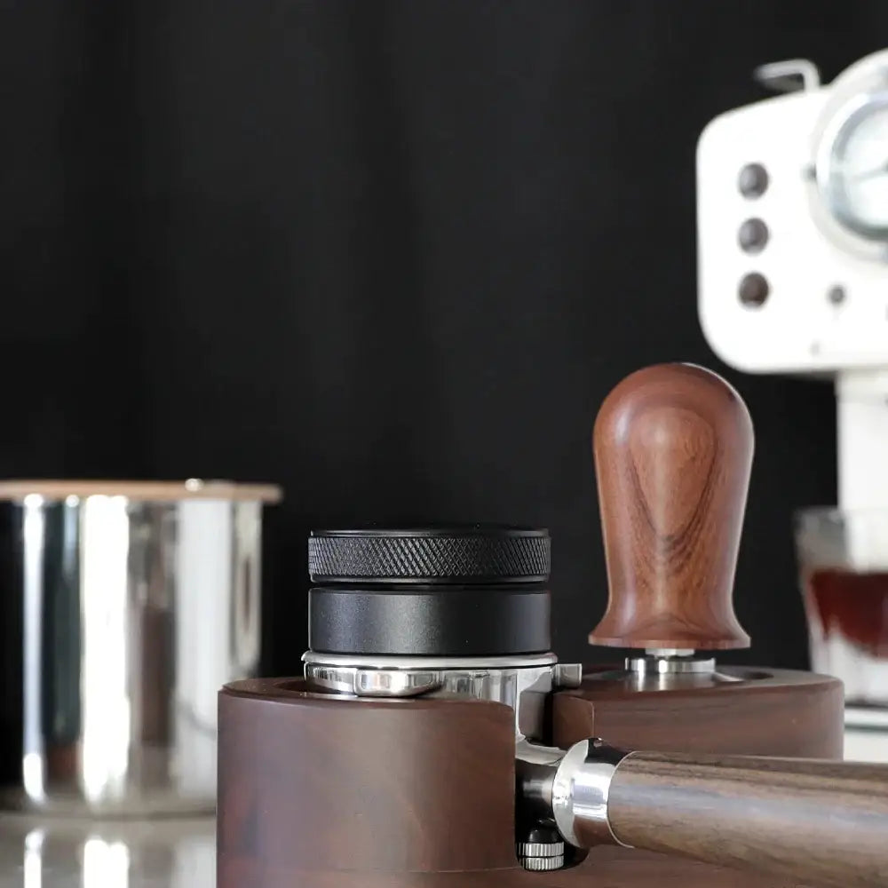 Dark brown wooden espresso distribution tool with polished ergonomic handle and black textured metal top for espresso distribution