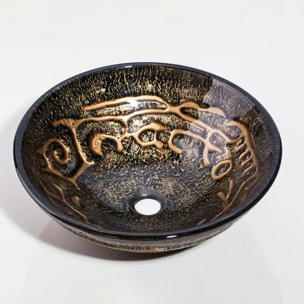 A sleek round glass wash basin with dark crackled finish and gold swirling patterns in textured basin set