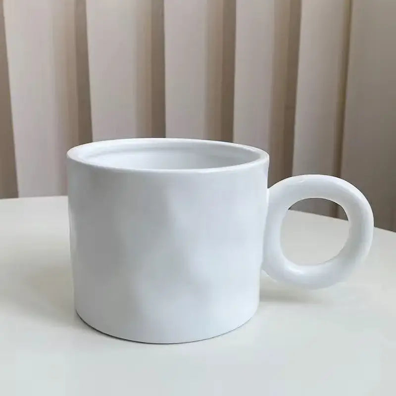 A minimalist white ceramic coffee mug with a smooth glossy finish and rounded handle for kitchen use
