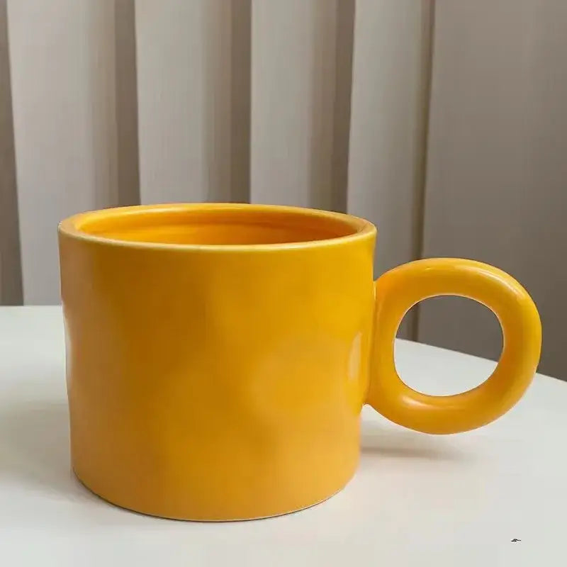 A vibrant yellow ceramic coffee mug with a smooth glossy finish and rounded handle ideal for kitchen use