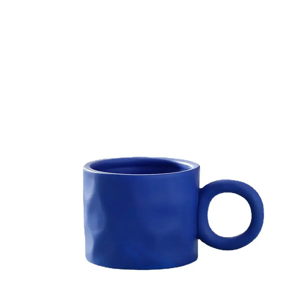 A vibrant cobalt blue textured ceramic coffee mug with a distinctive round handle for kitchen use