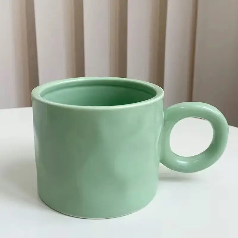 A smooth matte finished mint green ceramic coffee mug with rounded handle for kitchen use
