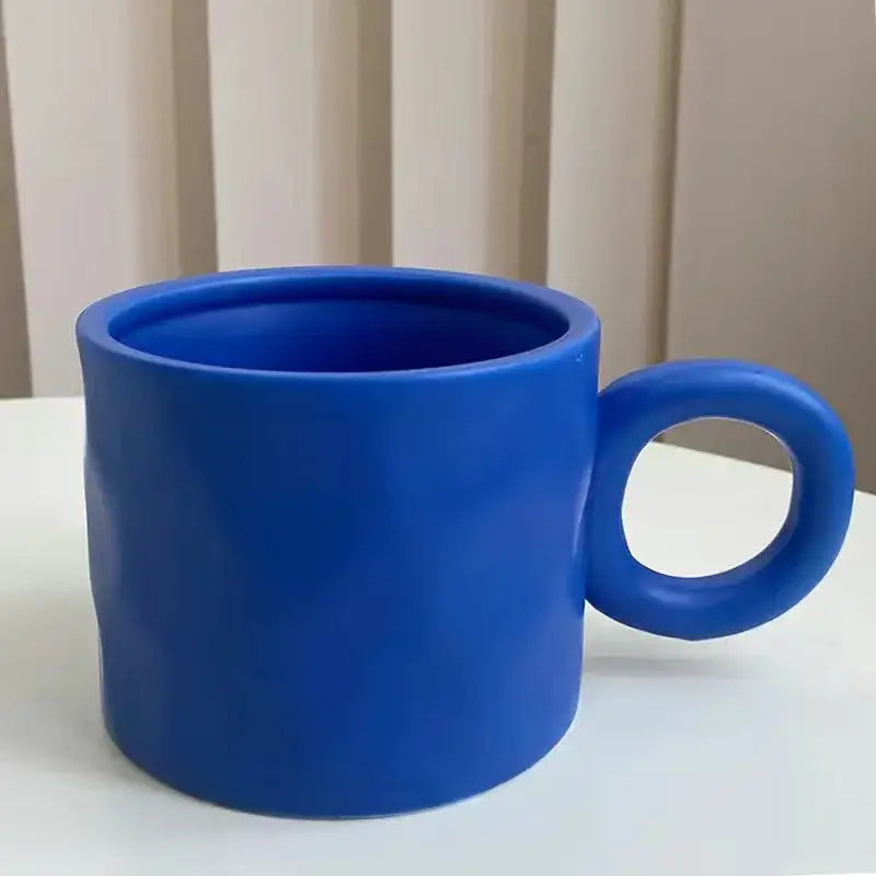 Solid cobalt blue ceramic coffee mug with a rounded minimalist handle and textured surface for kitchen use