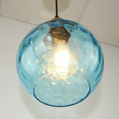 Translucent blue glass ball pendant light with textured bubble surface and brass fixture for dining room decorbites blue glass