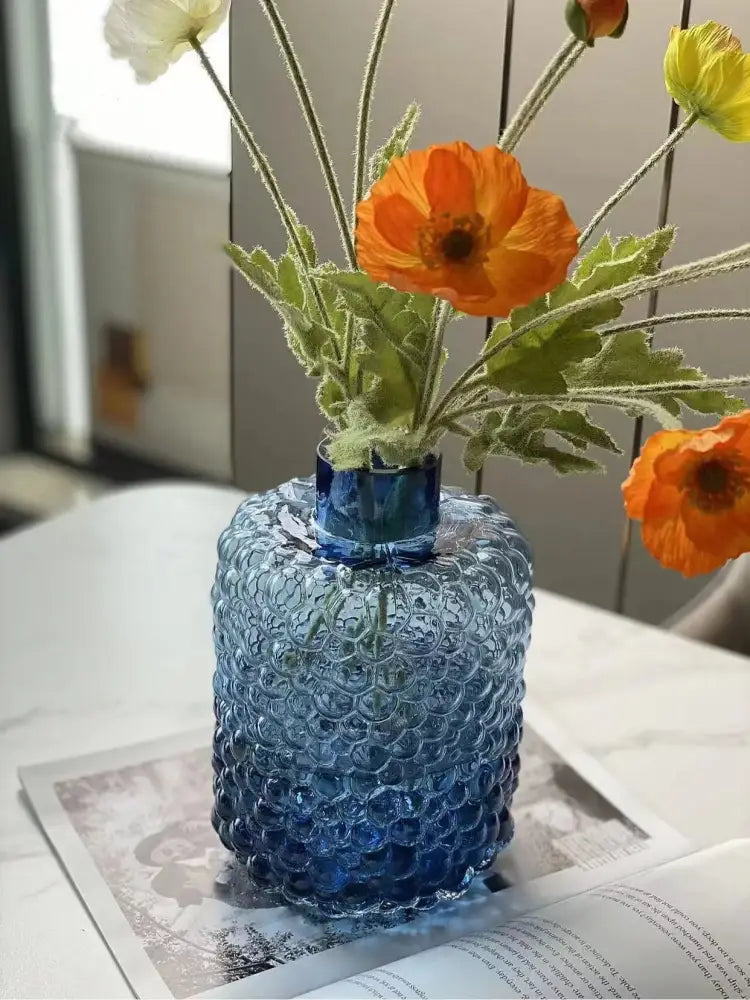 Textured blue glass flower vase with scalloped bubble pattern holding orange and yellow flowers for living room decorbites decor