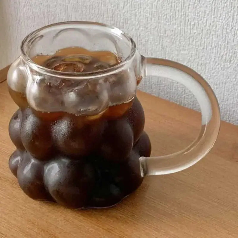 Clear glass mug with bubbly segmented design and smooth handle in a textured clear glass drinking set with gold spoon