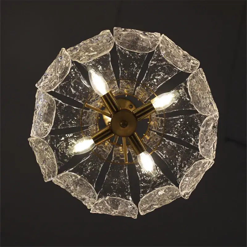 Textured clear glass french pendant chandelier with brass center and five illuminated bulbs for dining room lighting