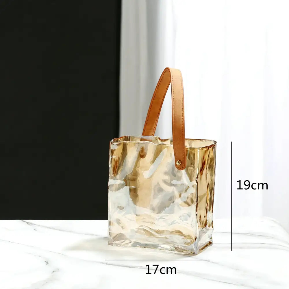 Transparent gold-tinged clear glass bucket bag with tan leather handle featured as decorbites clear glass vase decor