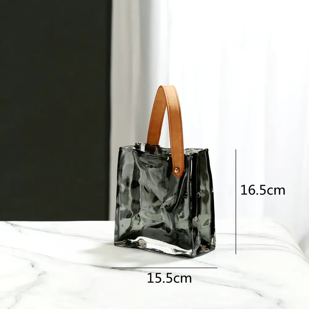 A sleek translucent black glass handbag with tan leather handle styled as decorbites clear glass living room decor