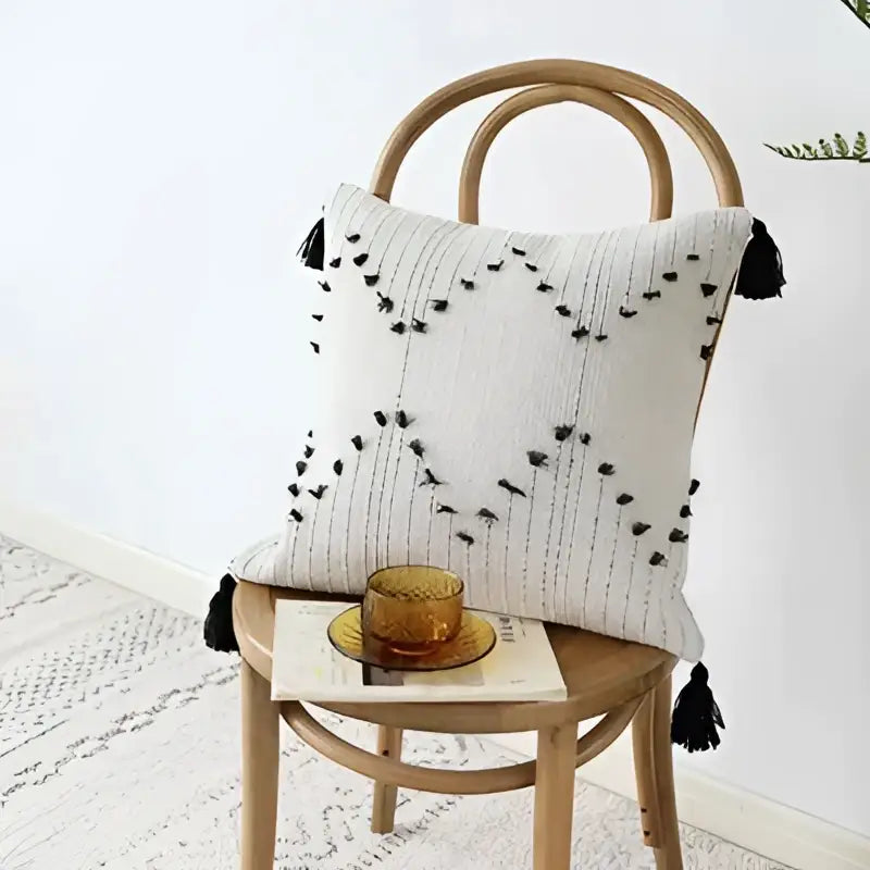 Off-white woven cushion cover with black decorbites geometric tassels and embroidered geometric patterns for living room decor