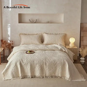 Cream cotton quilted bedspread set with textured pattern and fringed edges displayed in minimalist bedroom decorbites