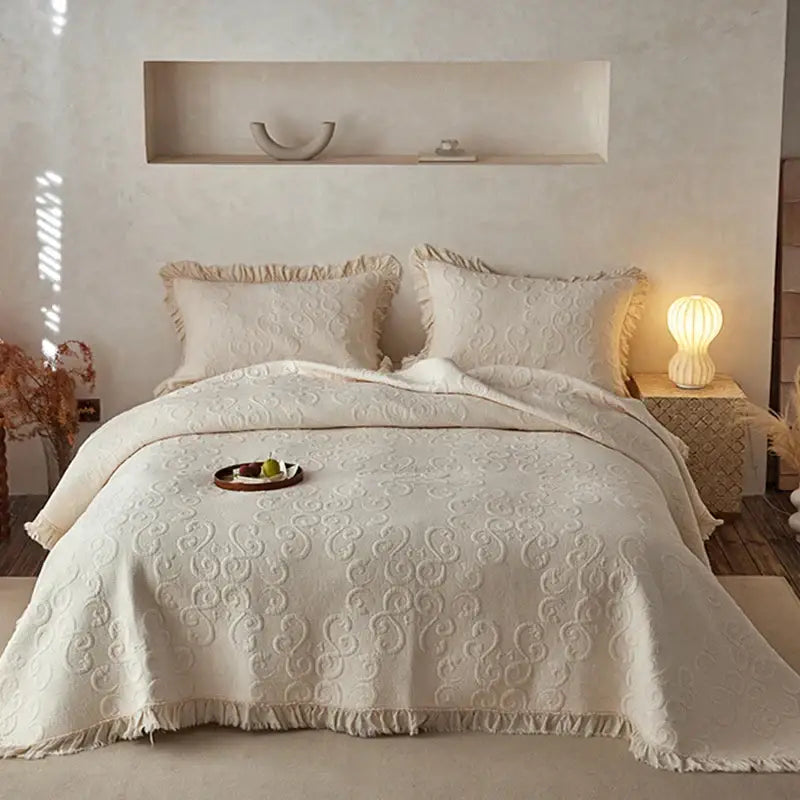Cream-colored decorbites cotton quilted bedspread set with intricate swirling patterns and fringed edges for bedroom decor