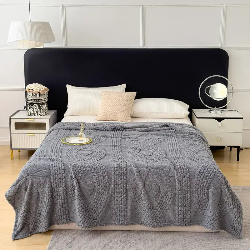 Gray textured throw blanket with plush knitted heart and geometric patterns used as a sofa cover blanket