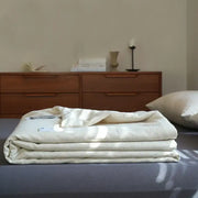 A neatly folded cream-colored linen cotton summer throw with subtle textured weave for decorbites linen cotton decor