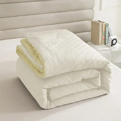 A neatly folded textured cream and pale yellow pillowcase quilt set with subtle pattern for bedroom bedding decorbites comforter
