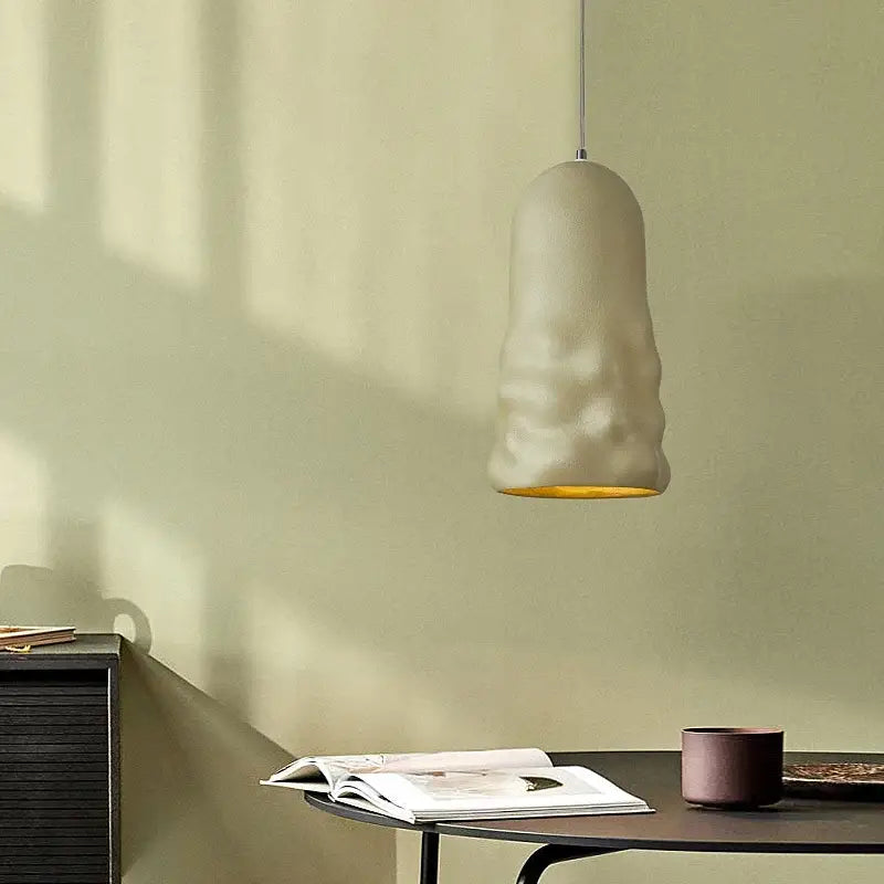 A matte white ceramic creamy wind pendant lamp with a textured organic shape and warm gold interior for dining decorbites