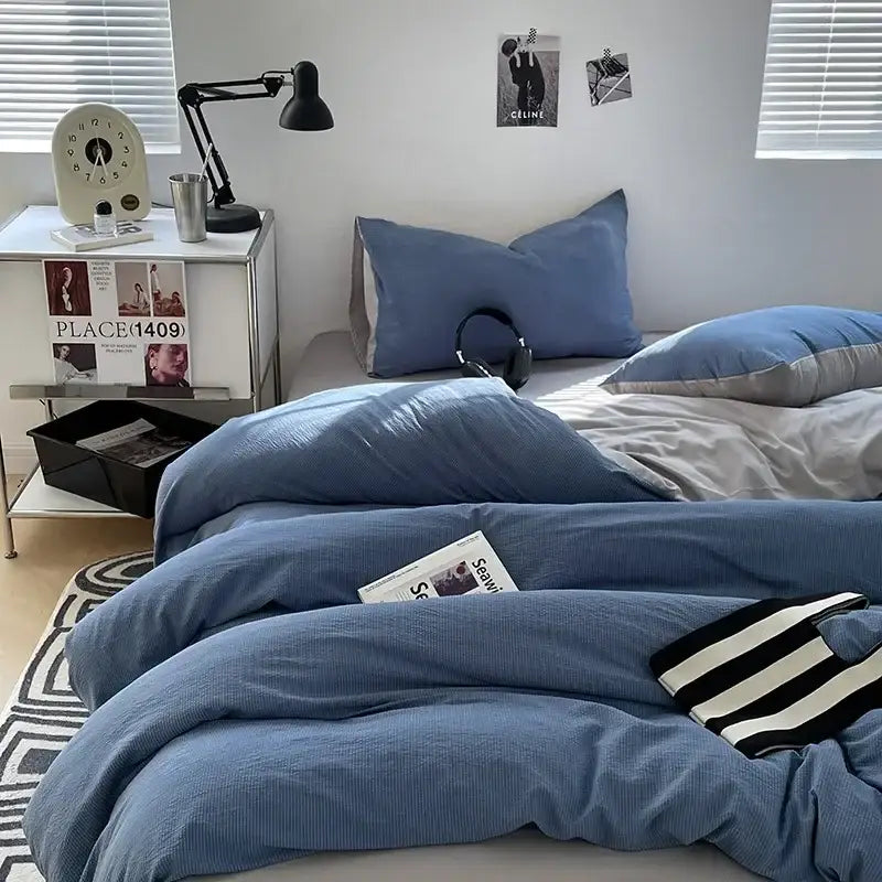 Blue textured duvet cover set with matching pillows and striped knit blanket on bed featuring bubble cotton quilt sets