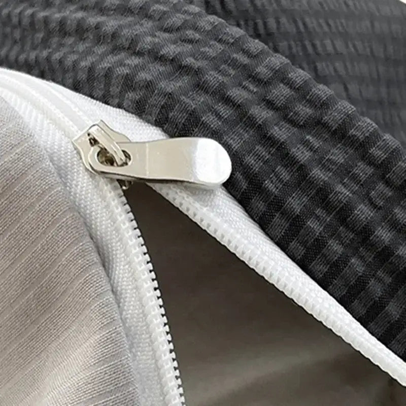 Silver zipper pull on a white zipper track on dark gray waffle-weave fabric of textured bubble cotton quilt sets