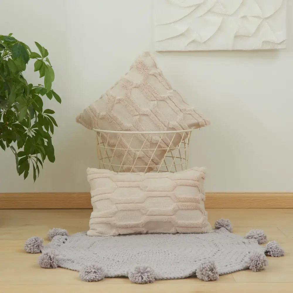 Beige textured throw pillows with diamond embroidery living pattern placed in wire basket and on pom-pom rug