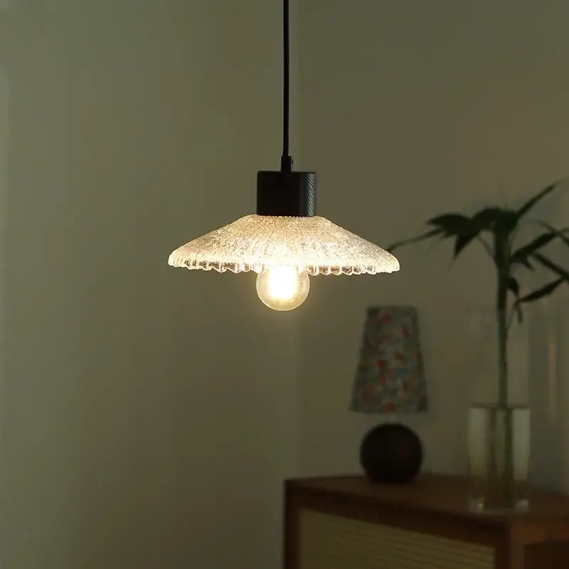 A warm glowing pendant light with a textured frosted clear glass shade and black metal fixture for kitchen decorbites clear glass LED lighting
