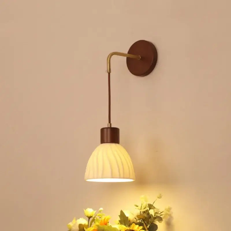 Warm-toned wall light fixture with ribbed off-white glass shade and dark wood metal arm for dining room use