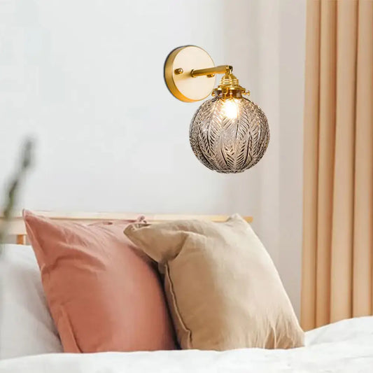 Textured glass ball wall light with etched spherical glass and gold-toned metal fixture for bedroom sconce lighting