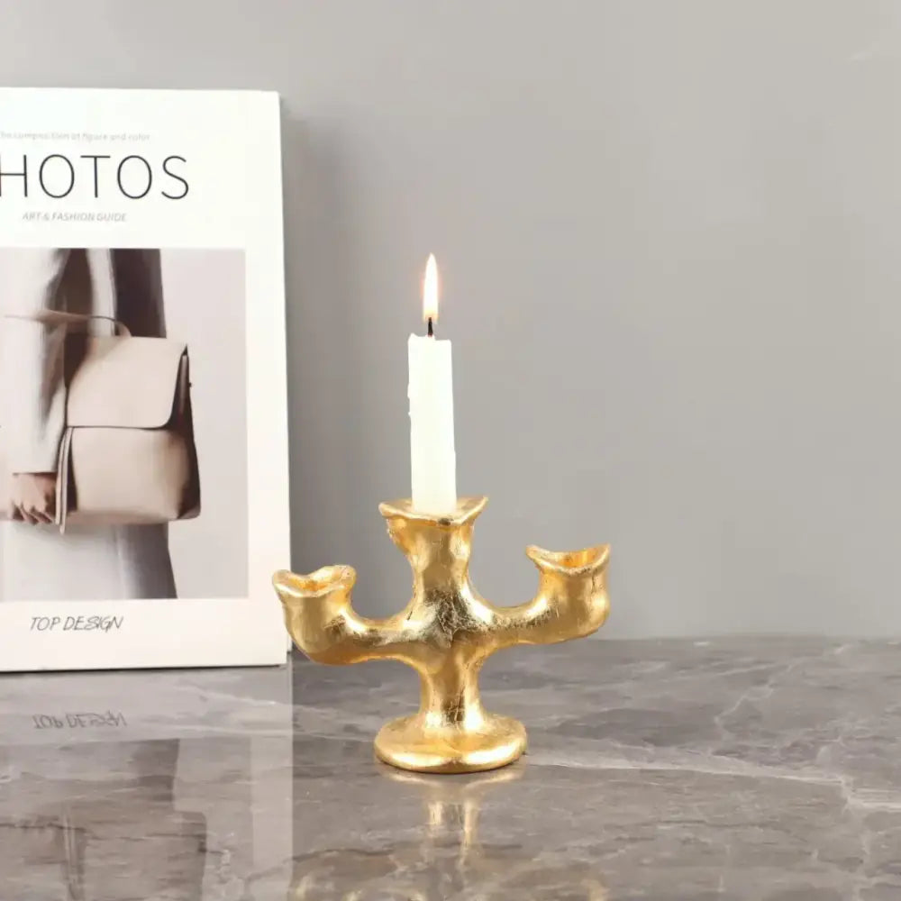 Gold-colored textured resin candle holder from decorbites holding a single white candle for dining room centerpiece